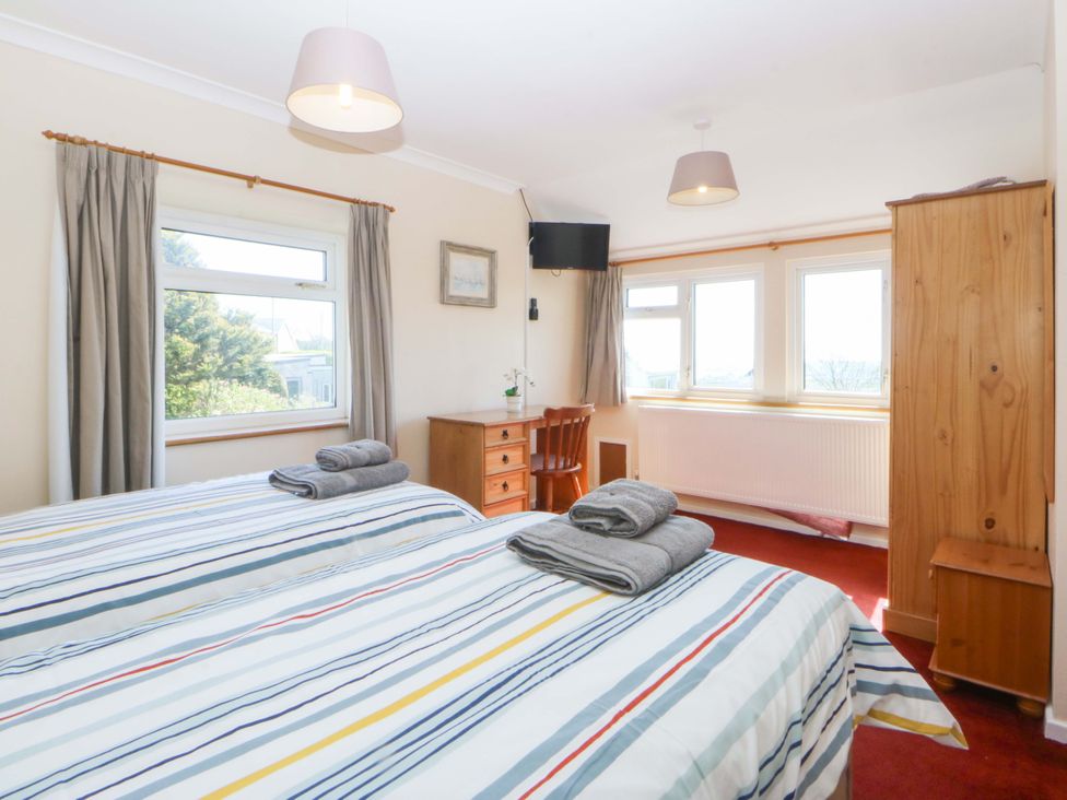 A bedroom with beds and a dresser at Pen Y Garth in Mynytho near Llanbedrog