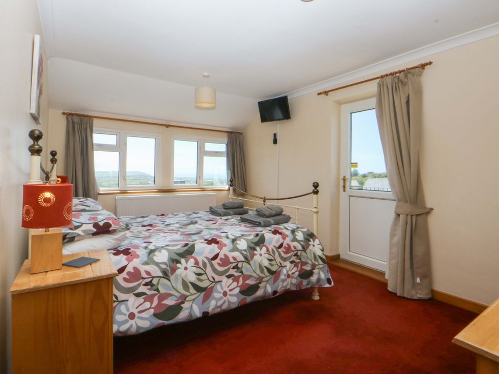 A bedroom with a bed and windows at Pen Y Garth in Mynytho near Llanbedrog