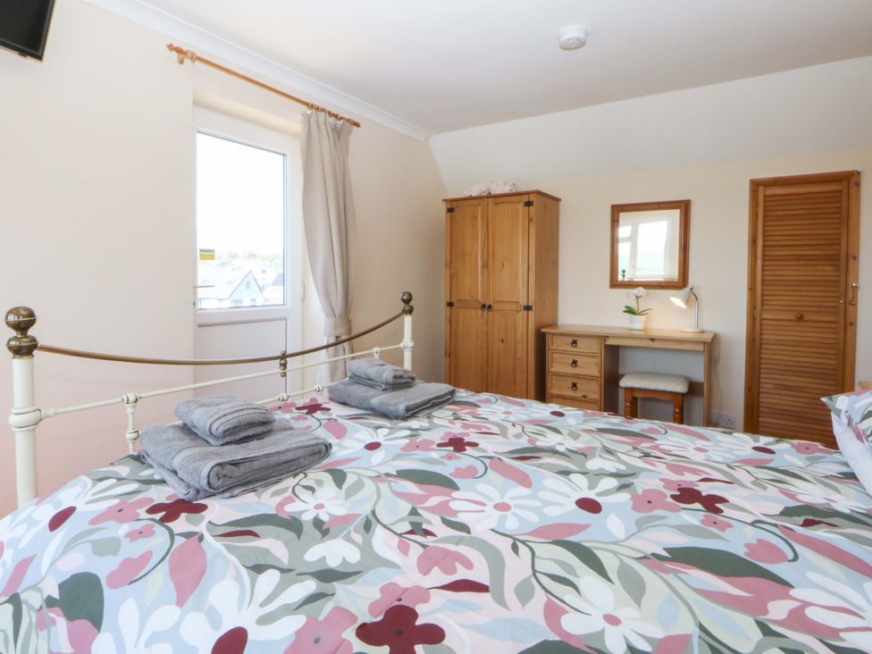 A bedroom with a bed and wooden furniture at Pen Y Garth in Mynytho near Llanbedrog