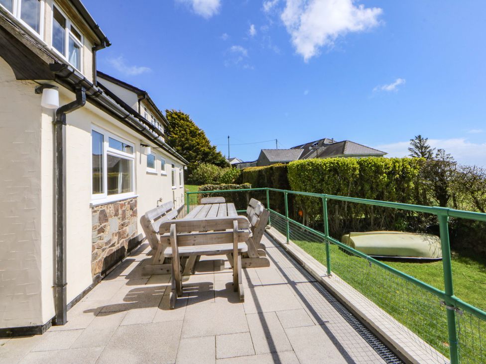 An outdoor area with a wooden table and chairs at Pen Y Garth in Mynytho near Llanbedrog