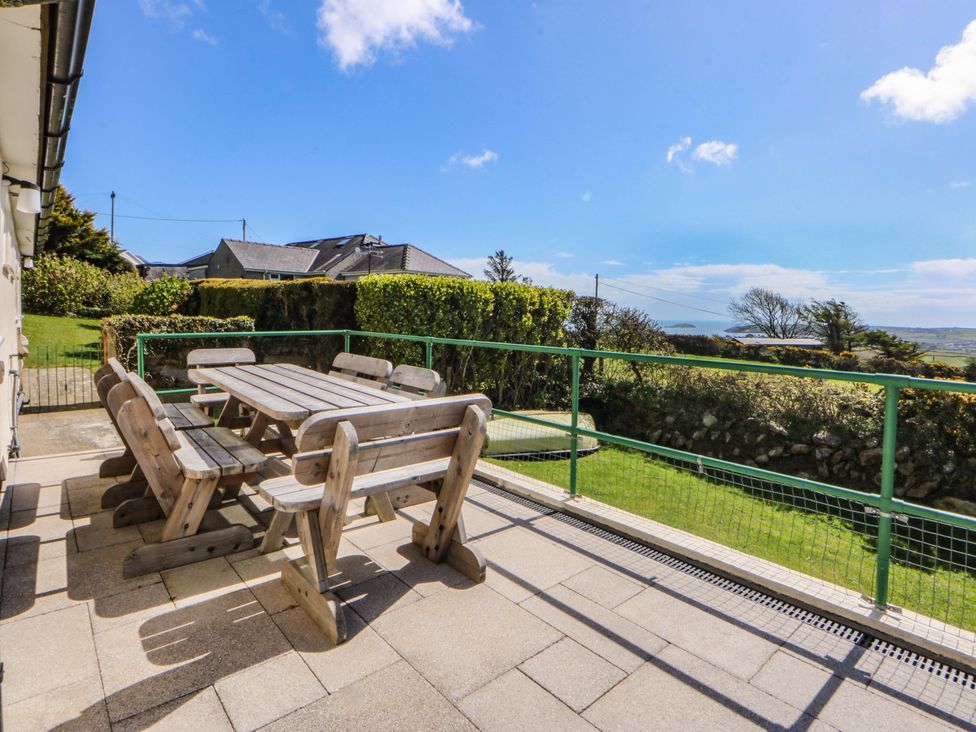 A patio with a wooden table and benches at Pen Y Garth Mynytho near Llanbedrog