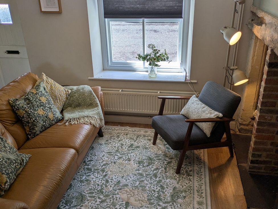A living room with a sofa and armchair at Troopers Cottage in Frome