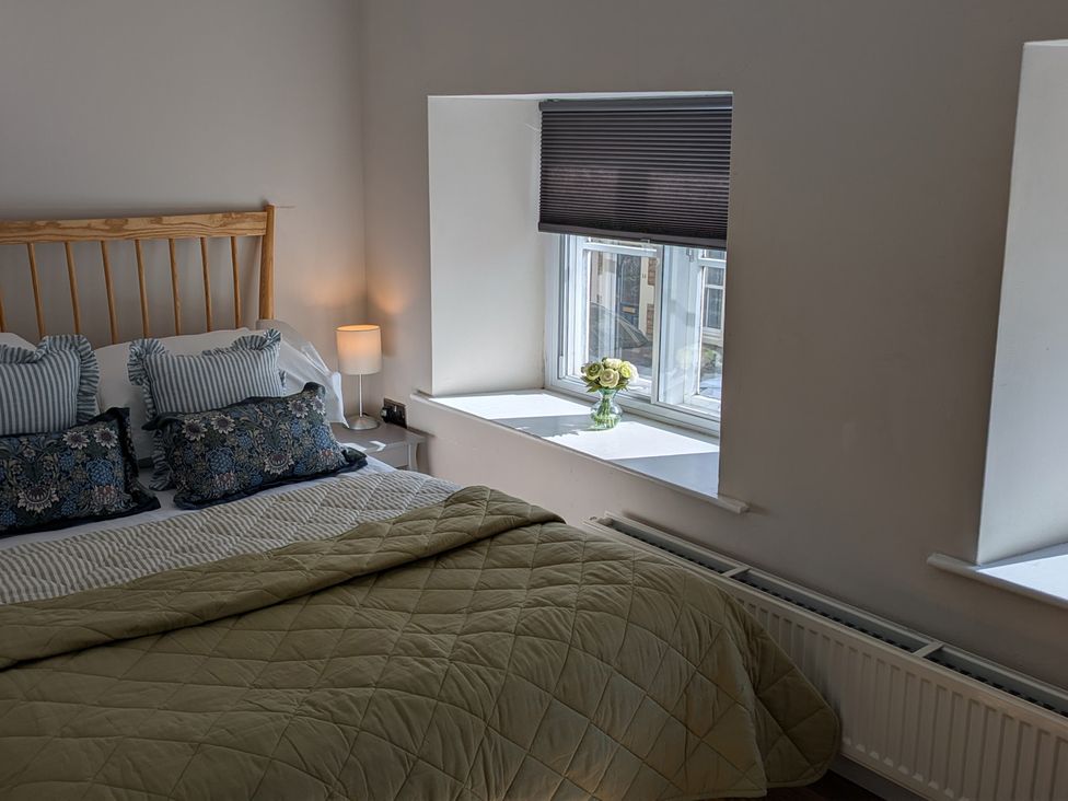 A bedroom with a bed and window in Troopers Cottage, Frome