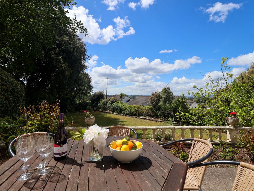 A garden with a table and chairs featuring a wine bottle and bowl of fruit at Holcombe House Torquay