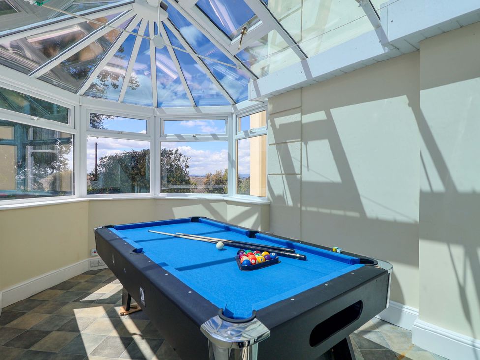 A conservatory with a pool table and windows at Holcombe House in Torquay