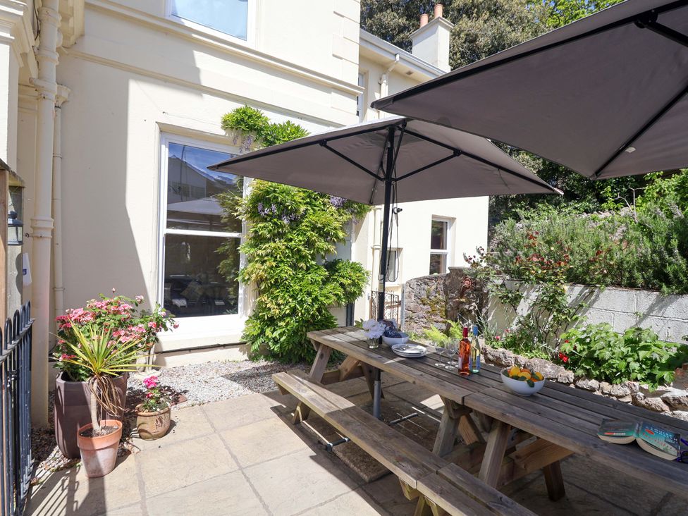 A garden with a picnic table and umbrellas at Holcombe House in Torquay