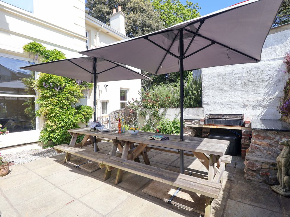 An outdoor seating area with a table and umbrellas at Holcombe House in Torquay