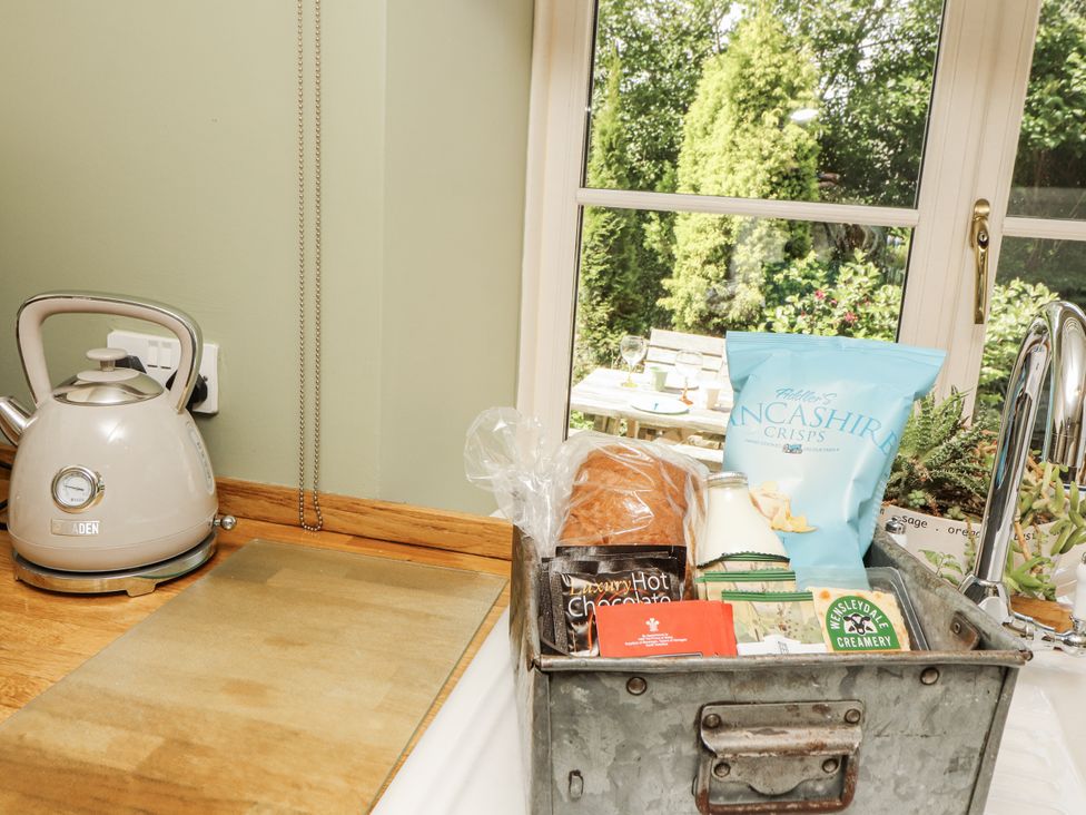 A kitchen with a kettle and a basket of snacks at Corner Cottage Ingleton