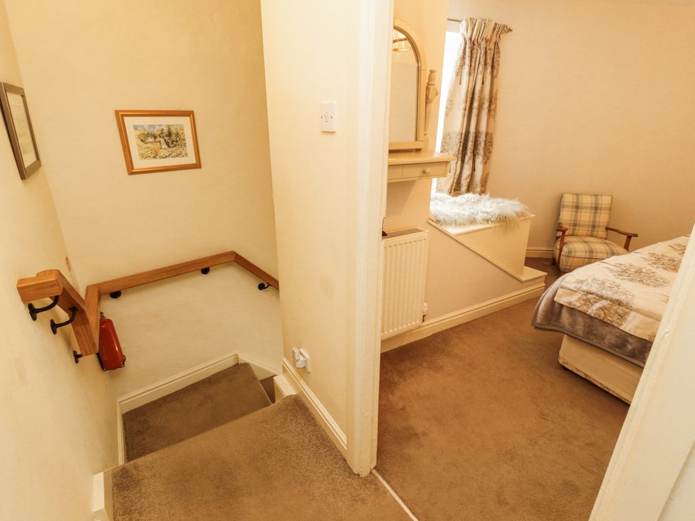 A bedroom with stairs and a chair at Corner Cottage Ingleton