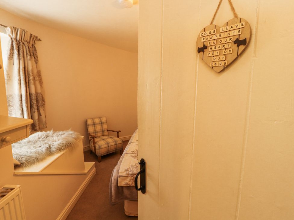 A bedroom with a chair and a heart decoration at Corner Cottage Ingleton