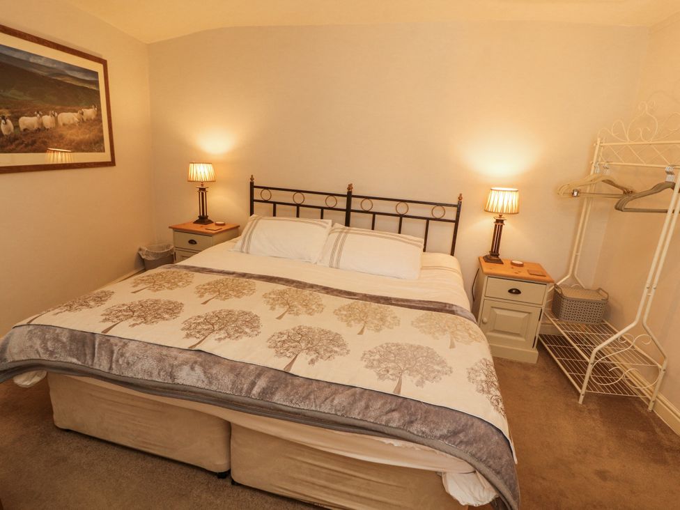 A bedroom with a bed and bedside table at Corner Cottage Ingleton