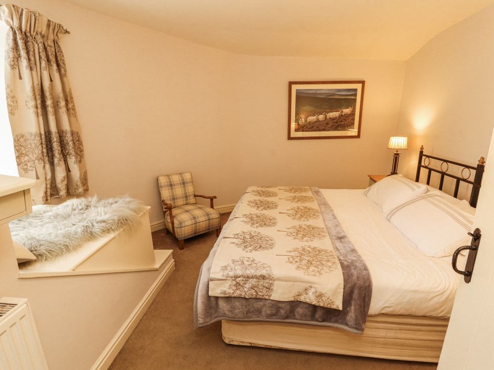 A bedroom with a bed and chair at Corner Cottage Ingleton