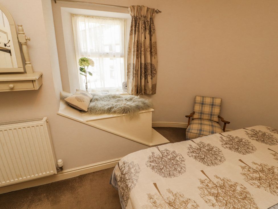 A bedroom with a bed and window seat at Corner Cottage Ingleton
