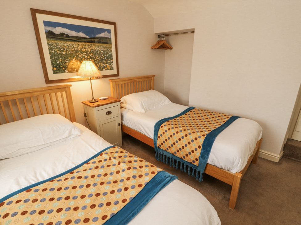 A bedroom with two single beds and a lamp at Corner Cottage Ingleton