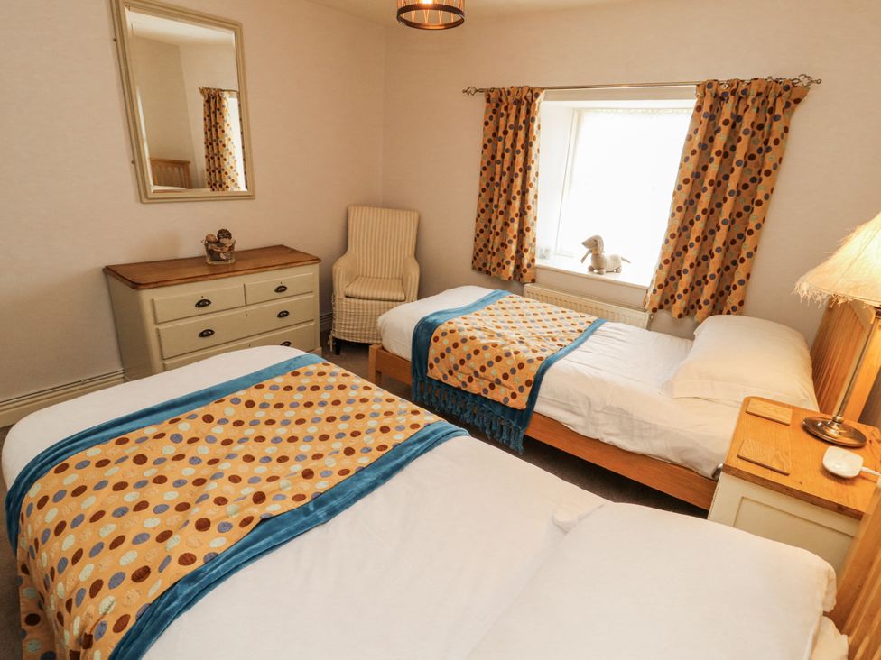 A bedroom with two beds and a dresser at Corner Cottage Ingleton