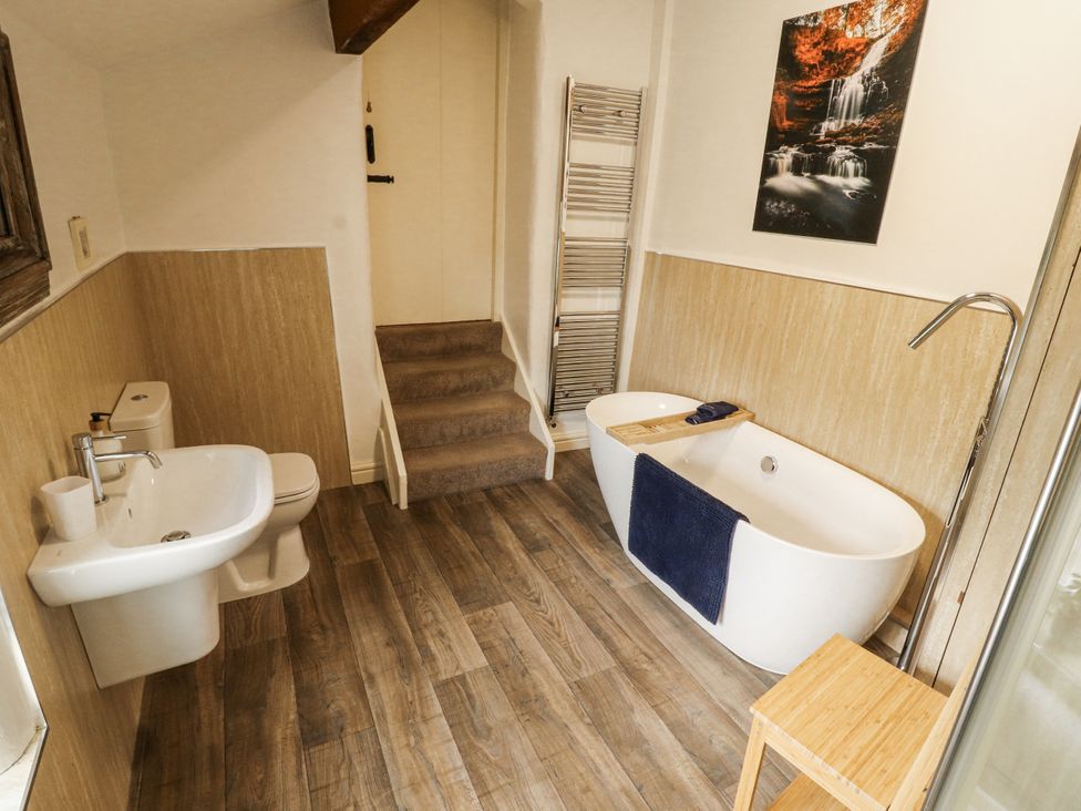 A bathroom with a bath, toilet, and sink at Corner Cottage Ingleton