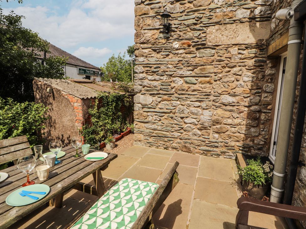 An outdoor terrace with a table and chairs at Corner Cottage Ingleton
