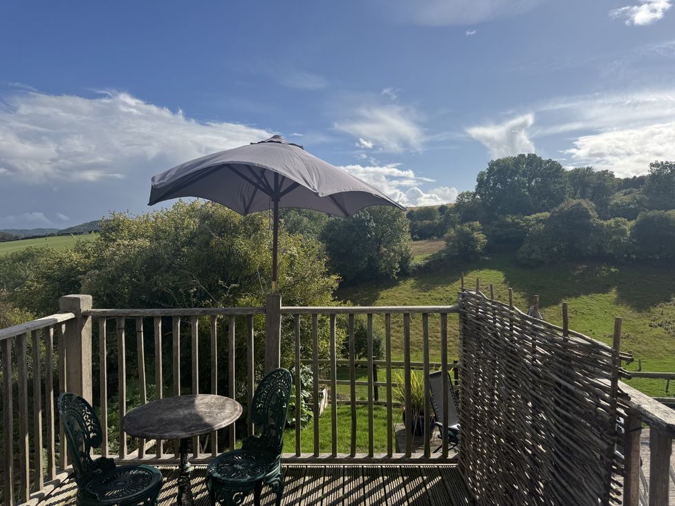 An outdoor area with a table and chairs under an umbrella at The Hideout in Llangrove