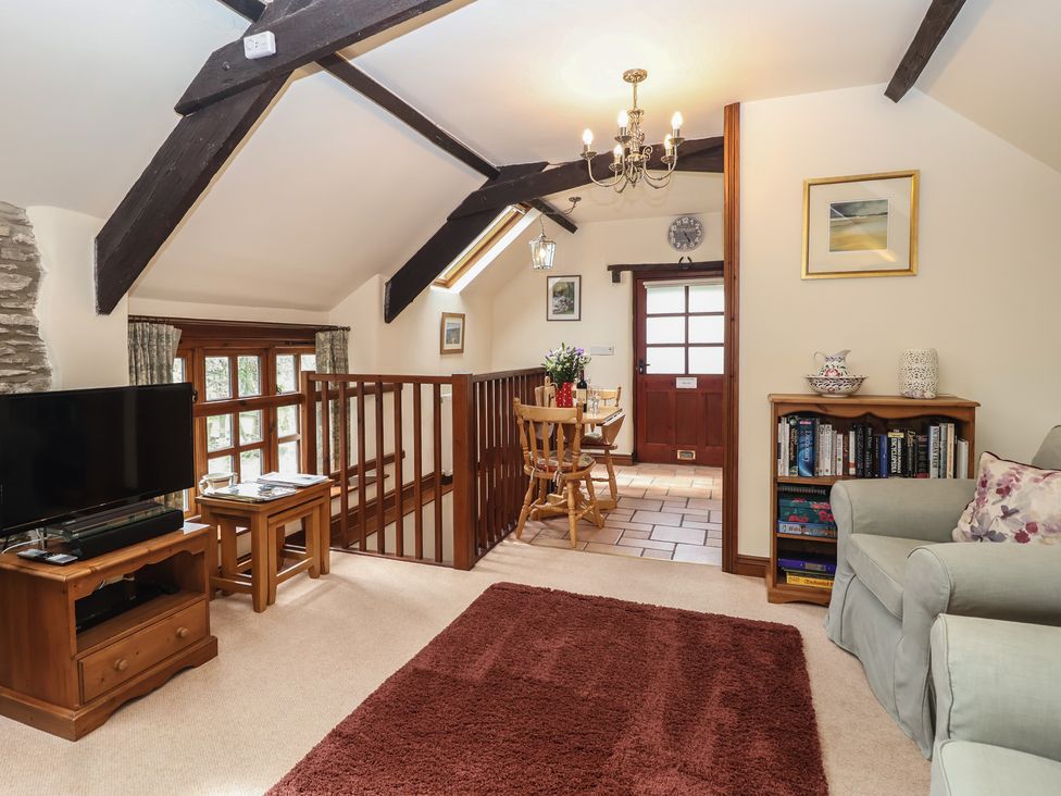 A living room with a television and dining area at The Coach House in Kingston