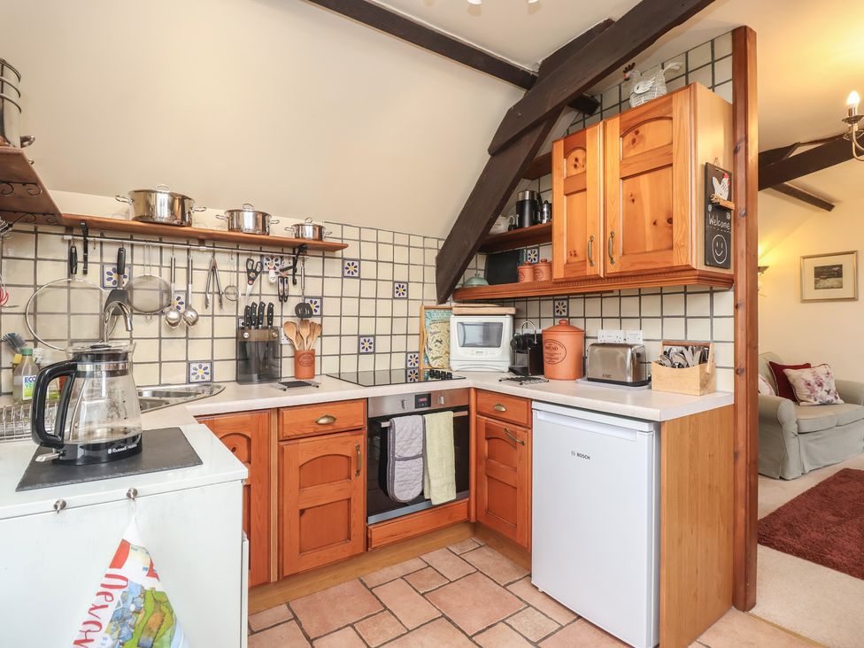 A kitchen with shelves, cooking pots, utensils, toaster, and microwave at The Coach House in Kingston