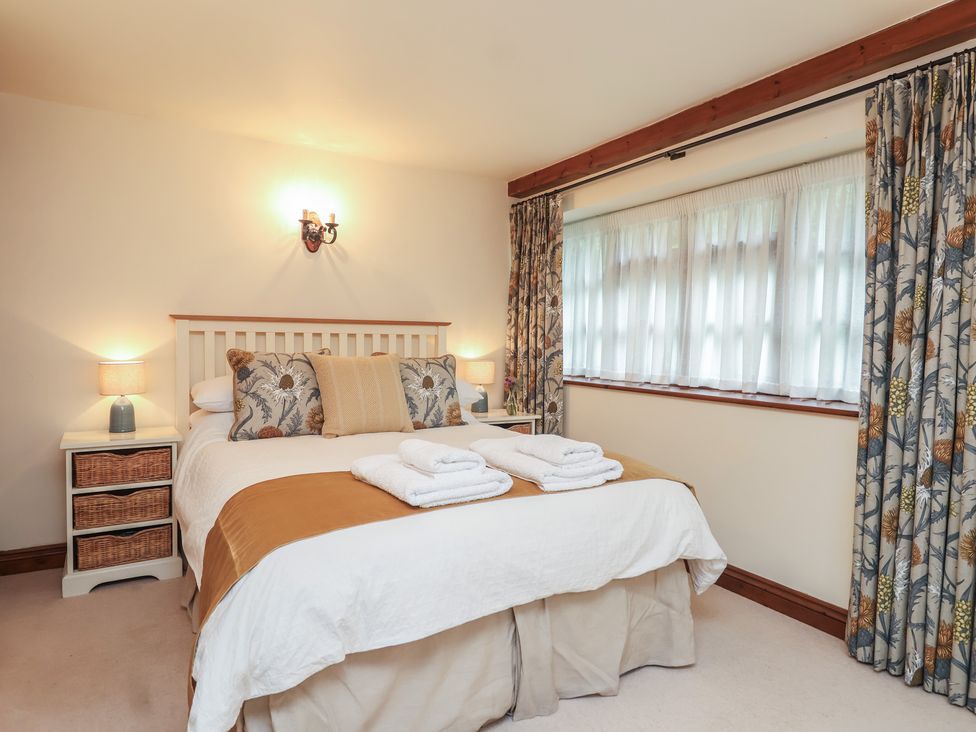 A bedroom with a bed, lamp, and curtains at The Coach House in Kingston