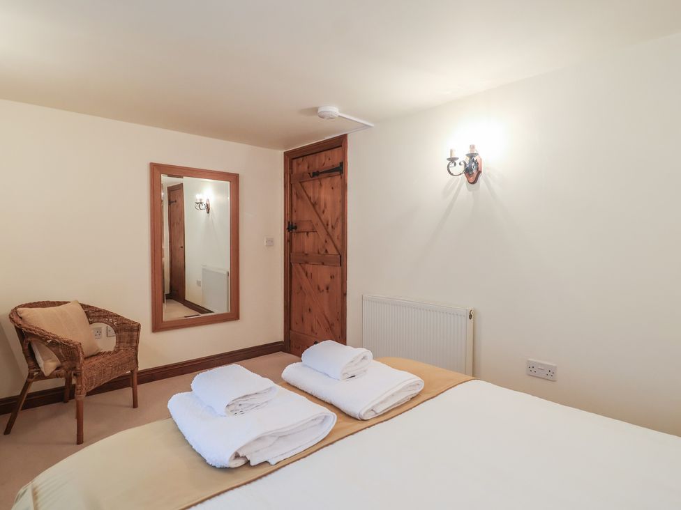 A bedroom with a bed towels and a mirror at The Coach House in Kingston
