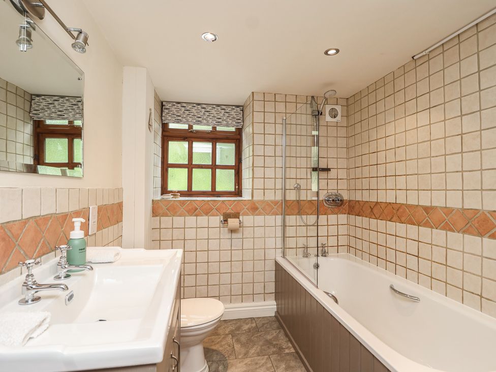 A bathroom with a bathtub, toilet, sink and shower at The Coach House in Kingston