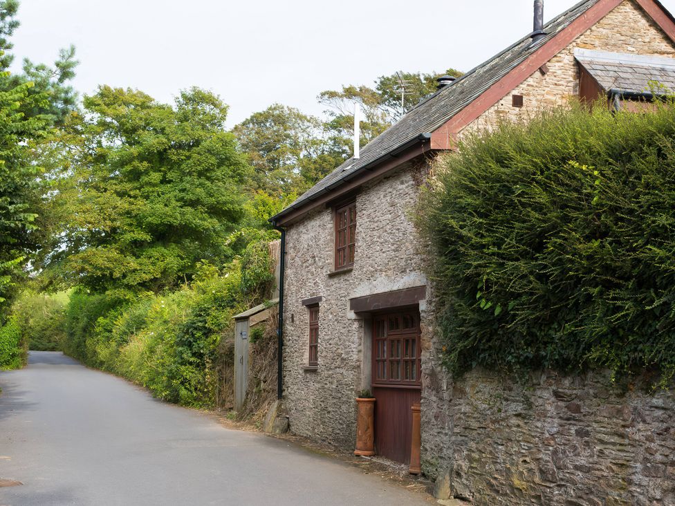 A house on a road surrounded by trees and bushes at The Coach House in Kingston