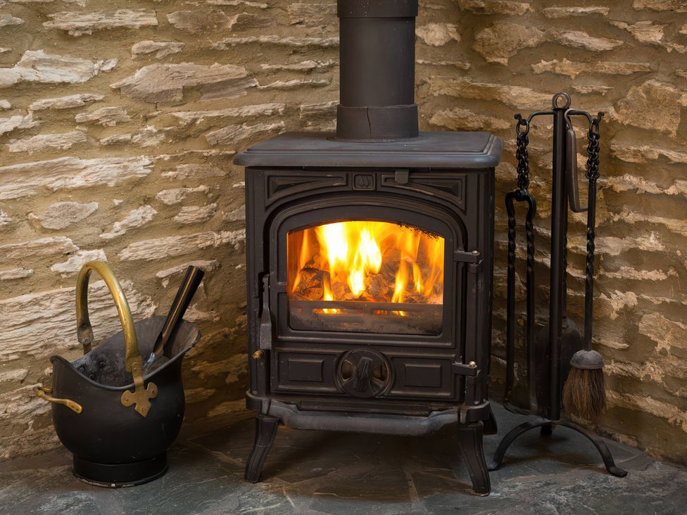 A wood stove with fire and ash bucket at The Coach House in Kingston