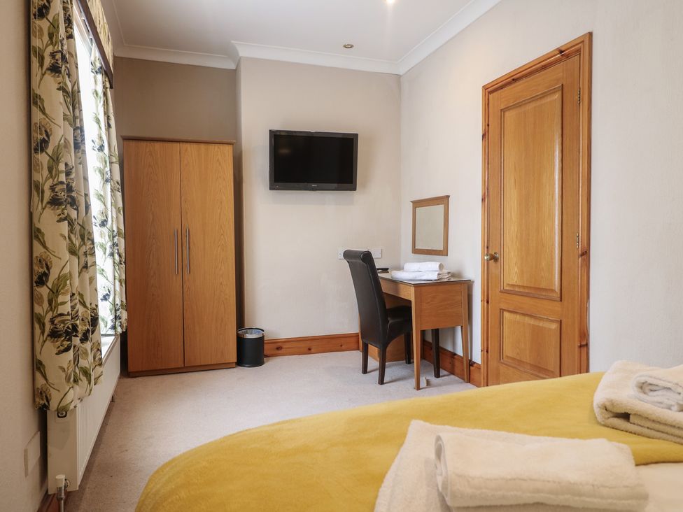 A bedroom with a bed, wardrobe, desk, and television at Hambleton House in Castle Donington