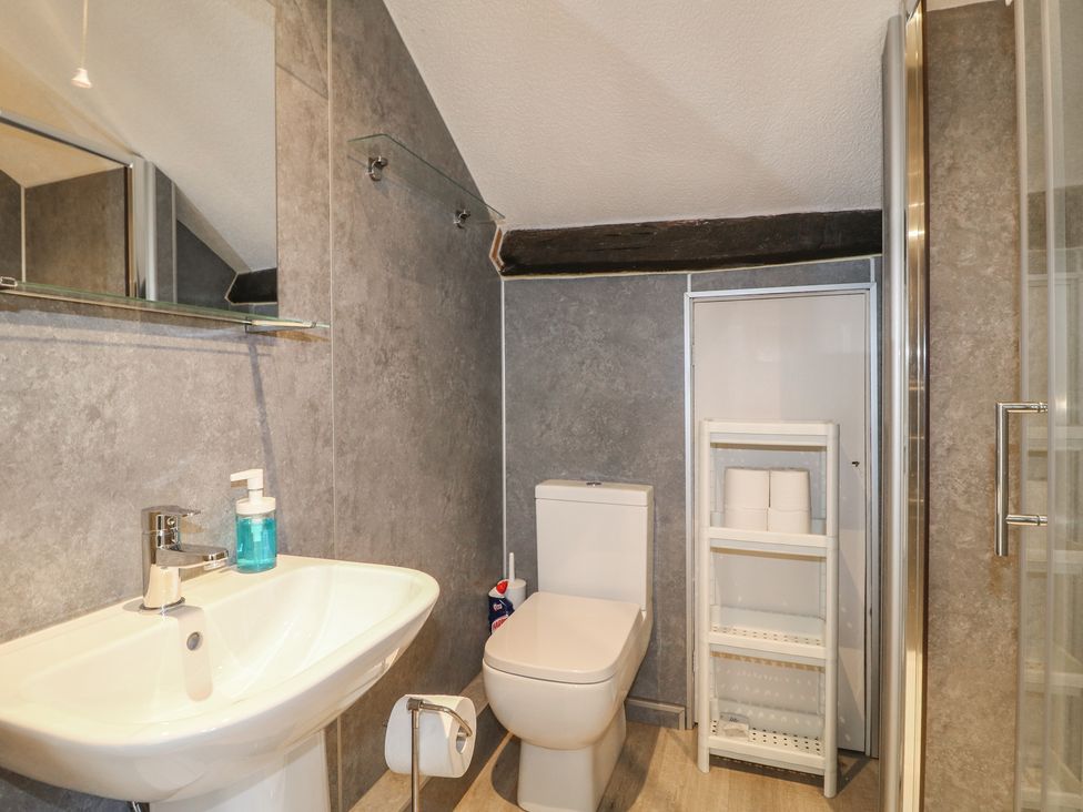 A bathroom with a sink, toilet, and shelf at Hambleton House in Castle Donington