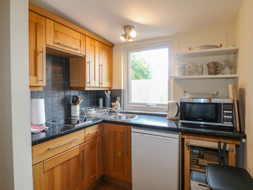 A kitchen with wooden cabinets and a microwave at Hambleton House in Castle Donington