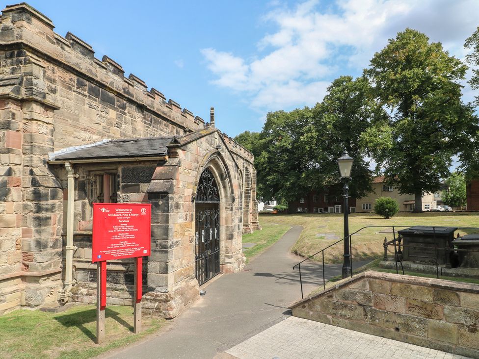 A church exterior with a sign and pathway at St Edward King and Martyr in Castle Donington