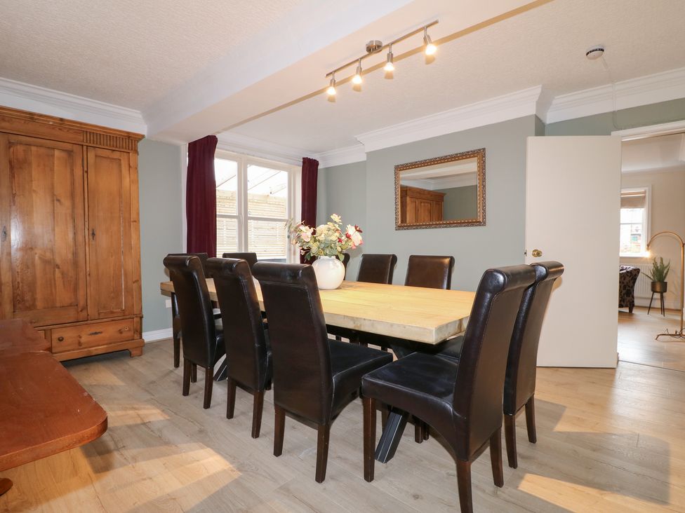 A dining room with a large table and eight chairs at Hambleton House in Castle Donington