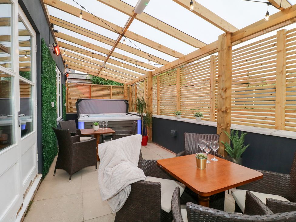 A conservatory with a hot tub and seating area at Hambleton House in Castle Donington