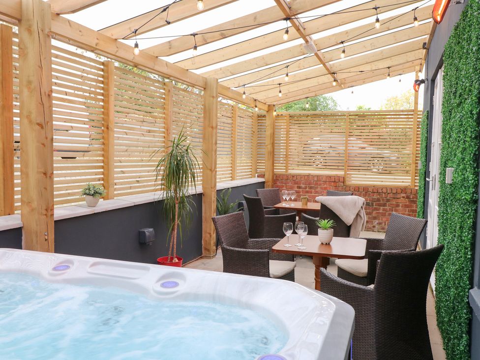 An outdoor seating area with a hot tub and furniture at Hambleton House in Castle Donington
