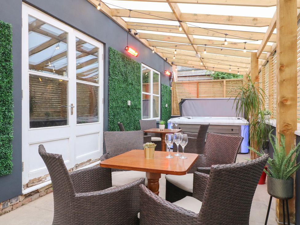 An outdoor patio with a seating area and hot tub at Hambleton House in Castle Donington
