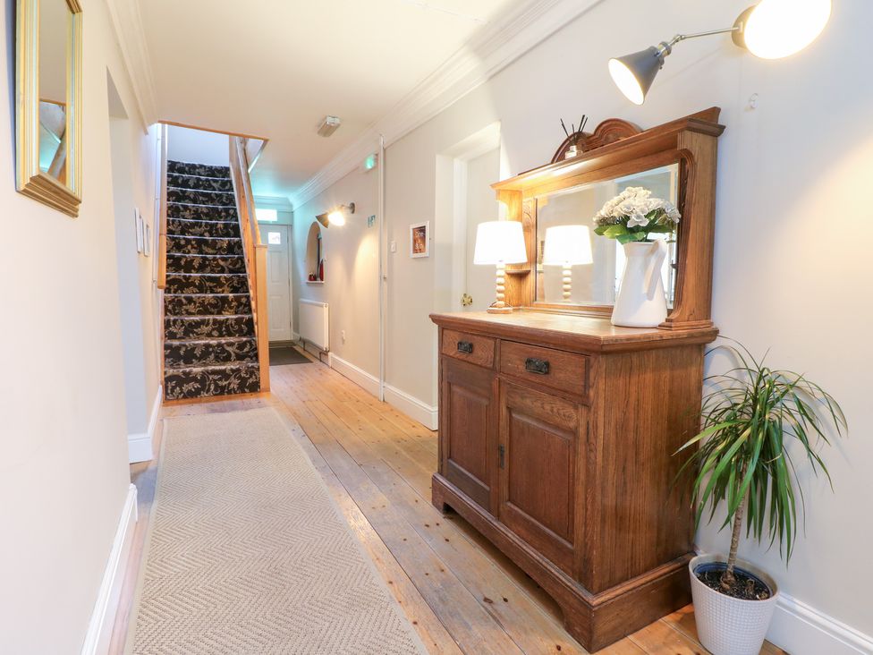 A hallway with a staircase, chest of drawers, and a plant at Hambleton House Castle Donington