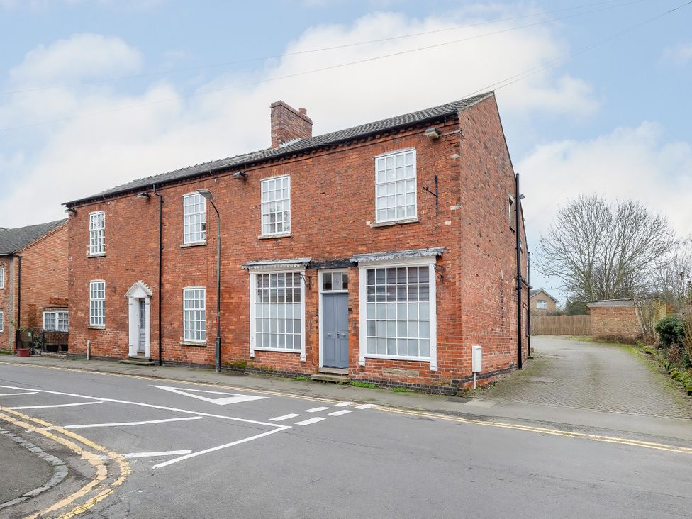 A brick house on the corner with windows and a driveway at Hambleton House in Castle Donington
