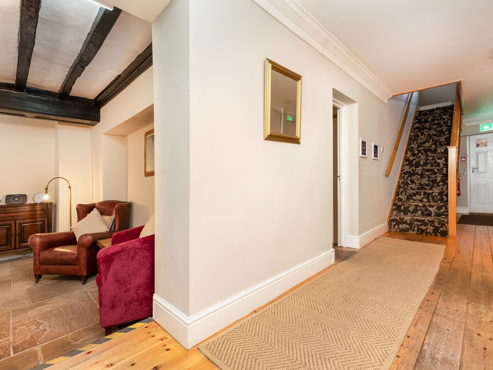 A hallway with an armchair and staircase at Hambleton House in Castle Donington
