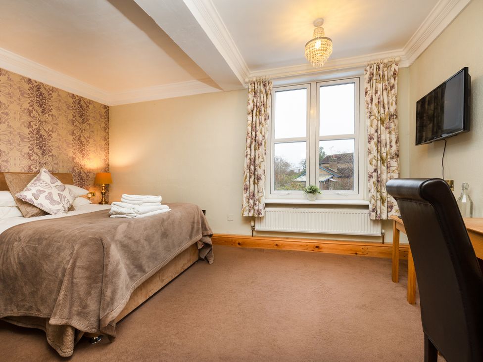 A bedroom with a bed, desk, and television at Hambleton House in Castle Donington