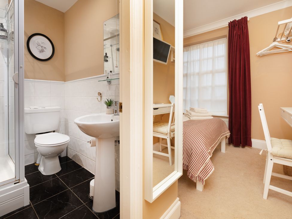 A bathroom with a sink and toilet and a bedroom with a bed and desk at Hambleton House in Castle Donington