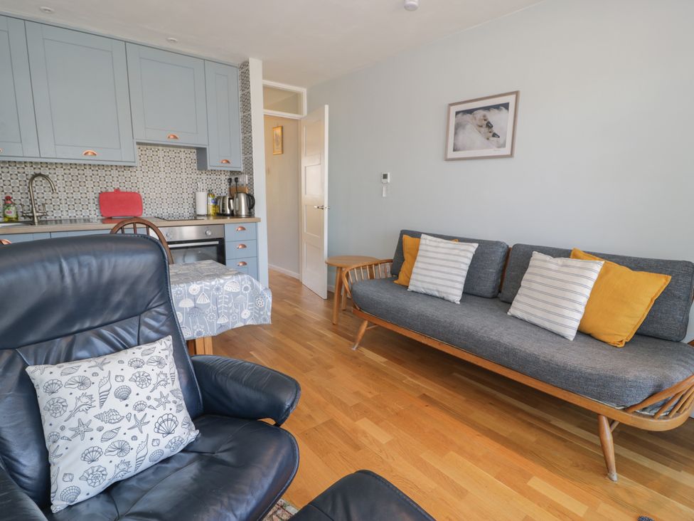 A living room with a sofa and a kitchen area at 56C South Snowdon Wharf in Porthmadog