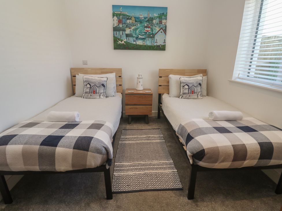 A bedroom with two beds and a bedside table at Sandpiper in Perranporth