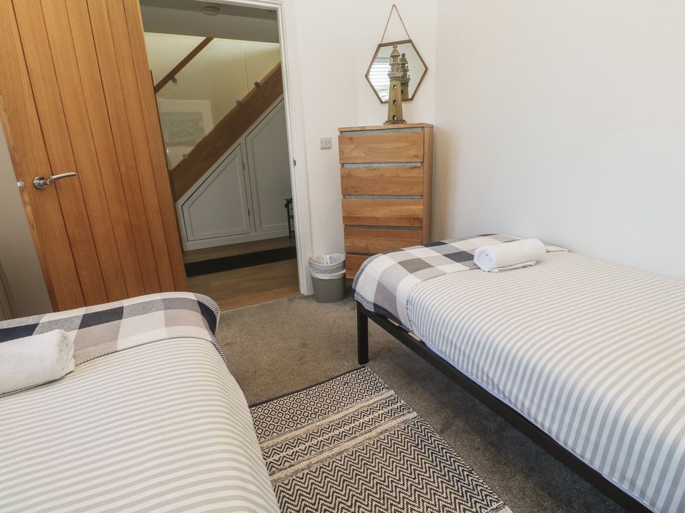 A bedroom with twin beds and a chest of drawers at Sandpiper in Perranporth