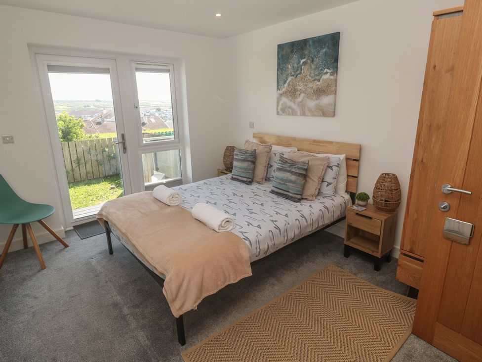 A bedroom with a bed and windows at Sandpiper in Perranporth