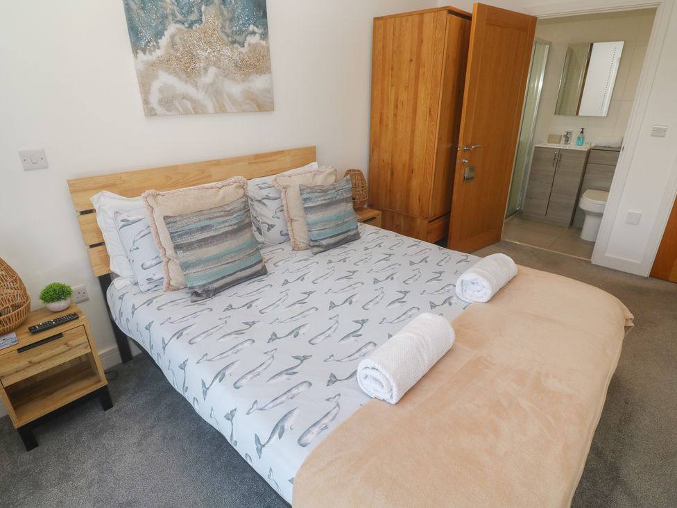 A bedroom with a bed and a wardrobe at Sandpiper in Perranporth