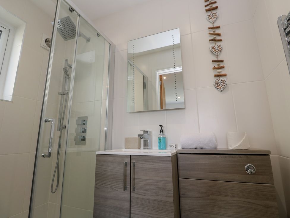A bathroom with a shower and sink at Sandpiper in Perranporth