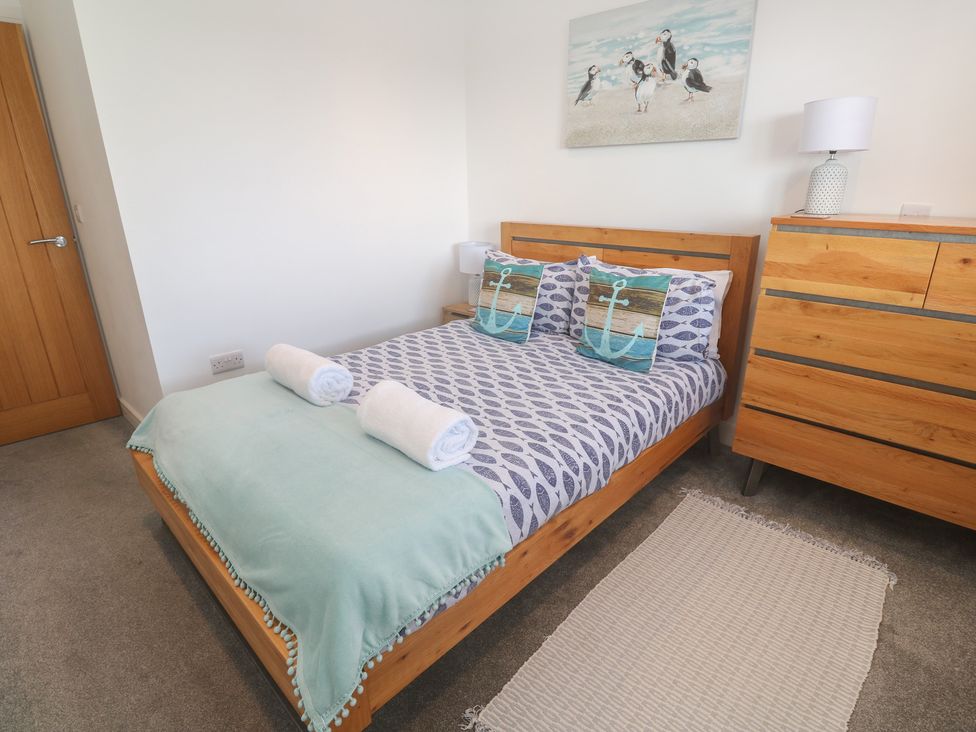 A bedroom with a bed, dresser and rug at Sandpiper in Perranporth