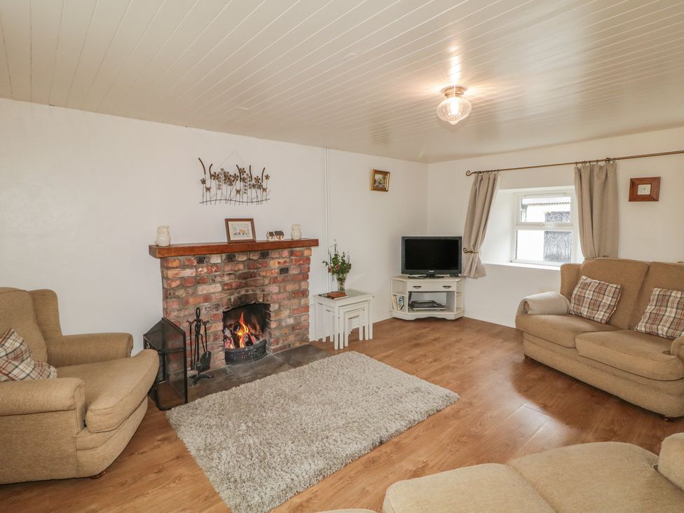 A living room with a fireplace and sofa at Shaws Hill Farmhouse in Kells, County Antrim